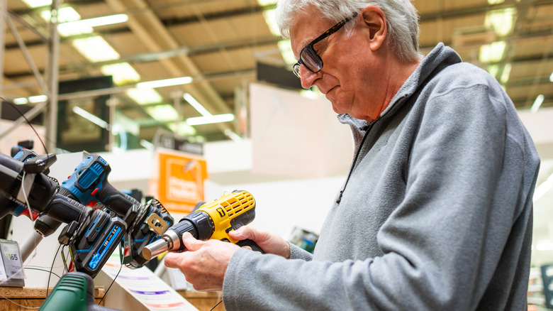 Older man looking at drills in a store.