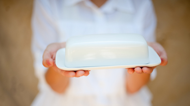 Someone holding a plain white butter dish
