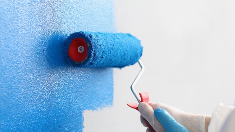 paint roller painting wall blue