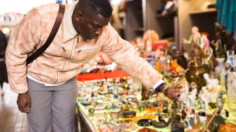 Person looks at items for sale displayed on a table at a flea market