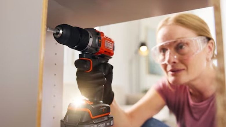 Woman using a cordless hammer drill to build a cupboard