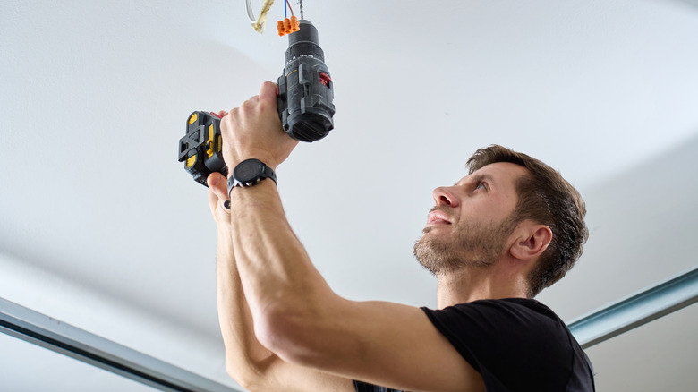Person using a cordless drill over head