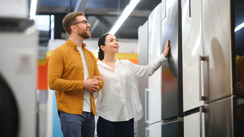Man and woman shopping for refrigerators