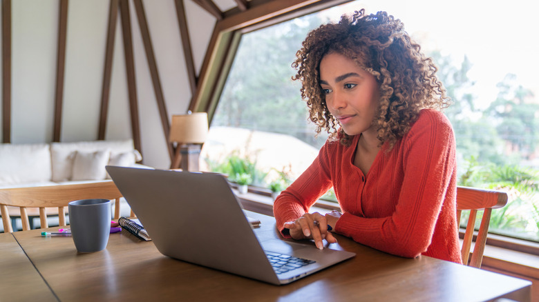 Woman researching on her laptop at a dining table