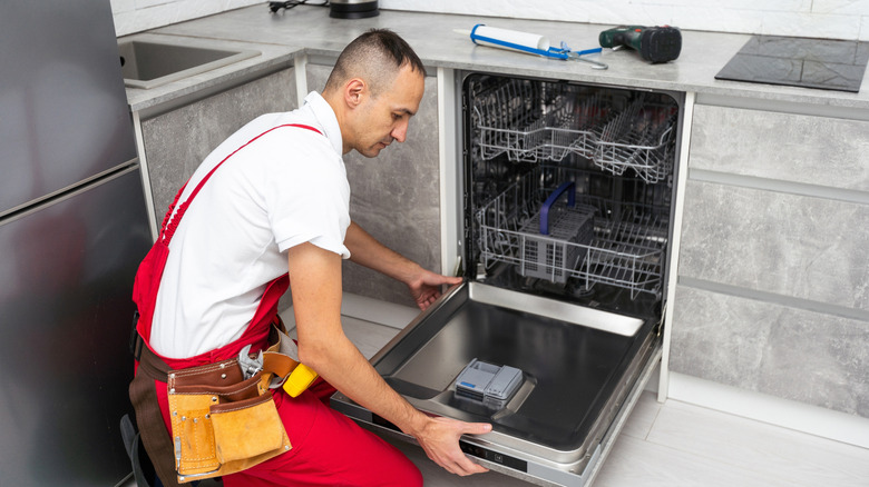 Repair person working on a dishwasher