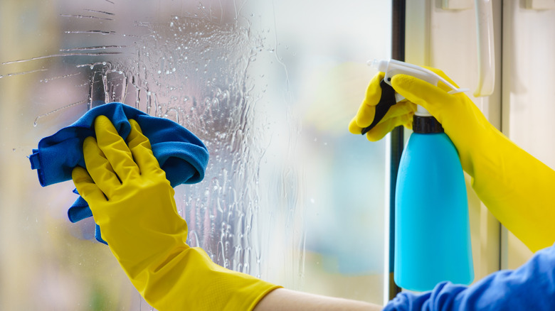 Cleaning window with microfiber cloth and spray bottle