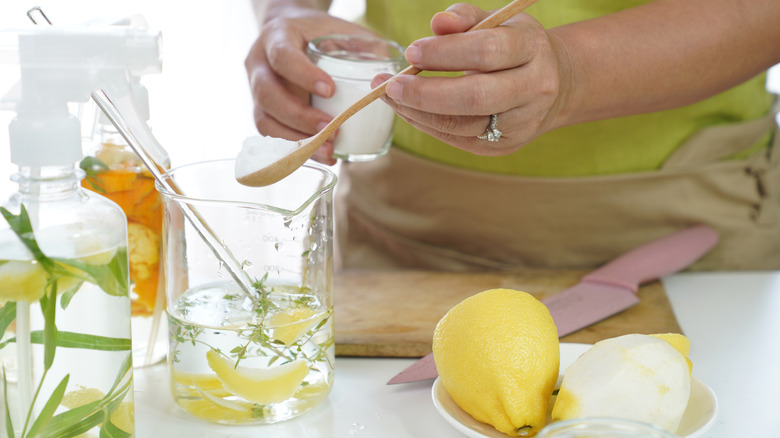 A person mixes a homemade cleaning solution in glass jars