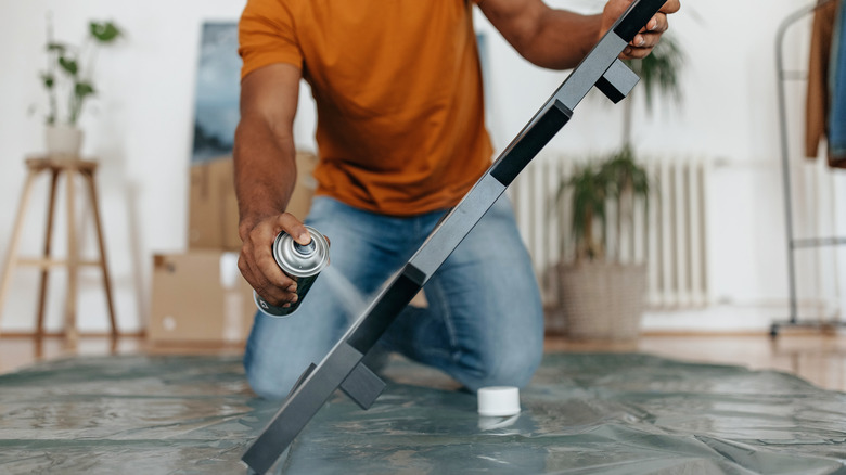 A man spray paints a DIY project