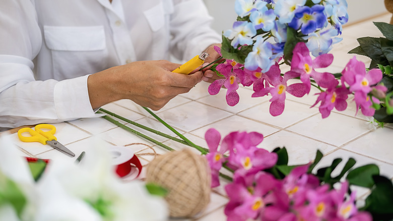 person creating a garland of plastic flowers