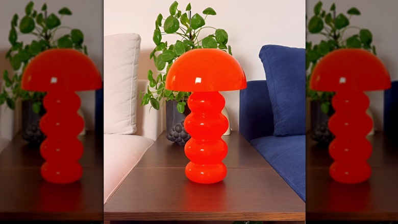 A DIY '70s inspired mushroom lamp in a bright orange color on a side table