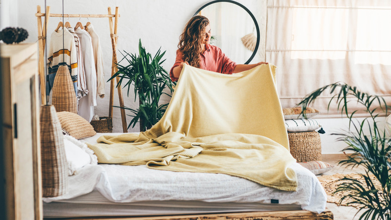 A woman makes the bed in a boho bedroom
