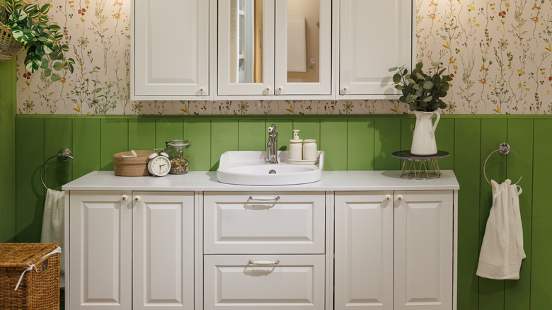 Windowless bathroom made brighter with chic floral wallpaper and green wall dimension