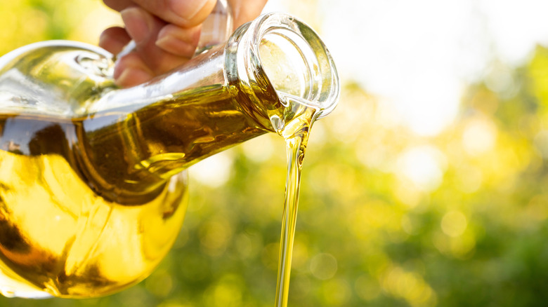 Close-up of oil pouring out of a glass container in a garden