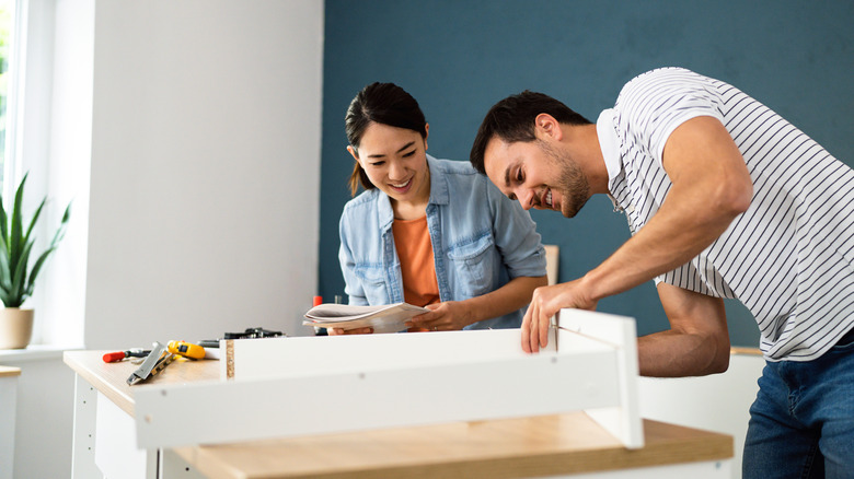 A couple building white furniture
