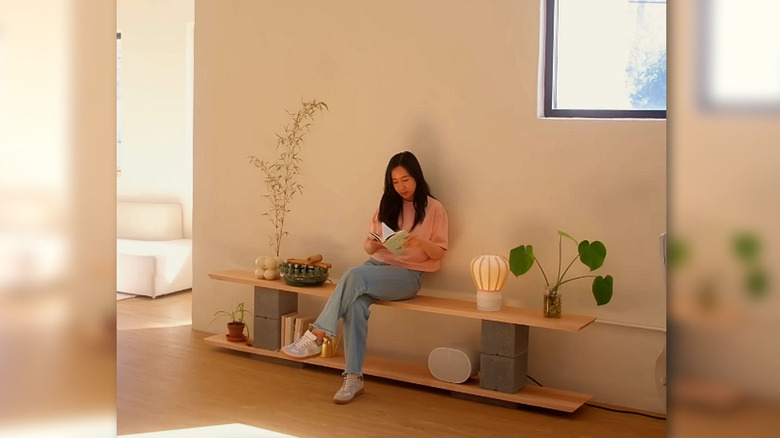 A shelf made with stone blocks and wooden plants with a girl sitting on it