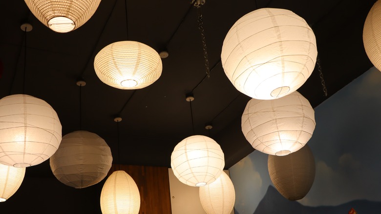 A collection of hanging paper lanterns glow against a dark background.
