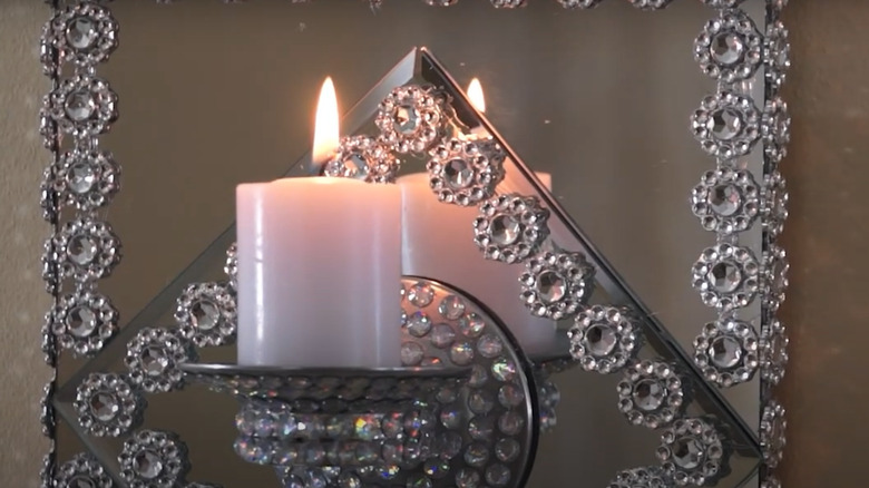 A mirrored sconce holds a lit candle.