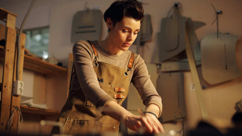 An artisan with short, dark hair works with wood in their workshop.