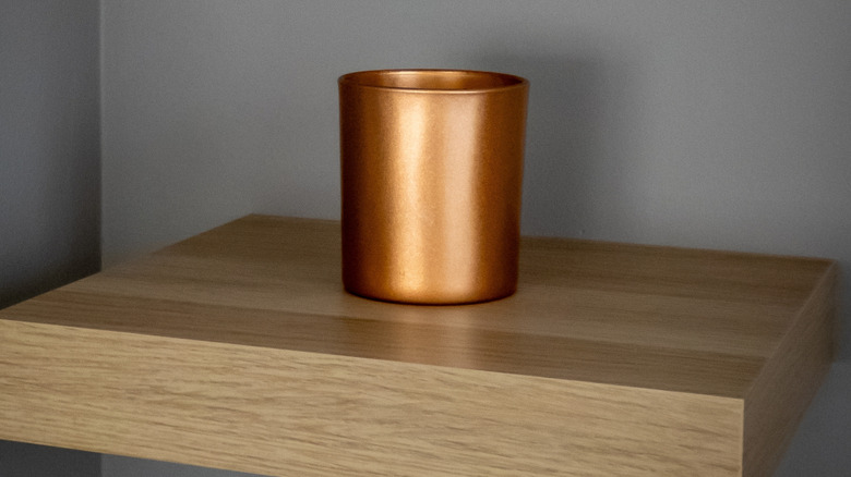 A shiny copper decor piece on a wood shelf
