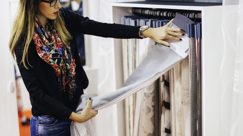 stylish woman choosing curtain fabric in a store