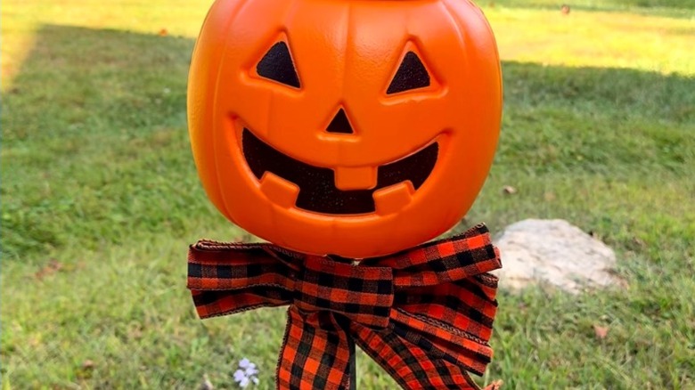 A light-up pumpkin head on a stand in yard