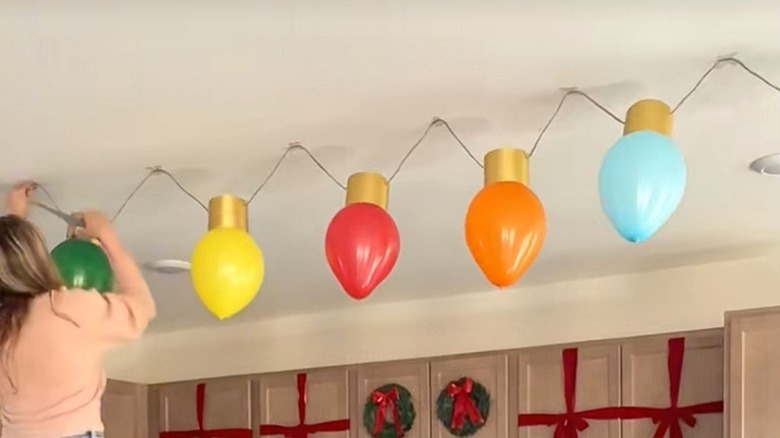 Woman hanging oversized Christmas light decorations from the ceiling