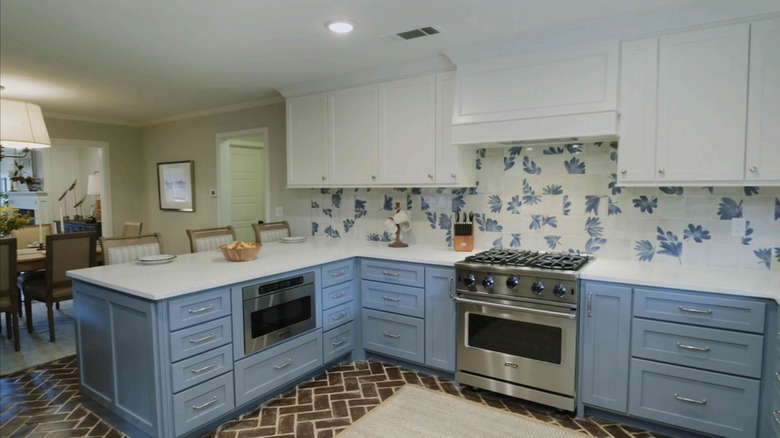A kitchen with blue and white cabinets and a peninsula with stools