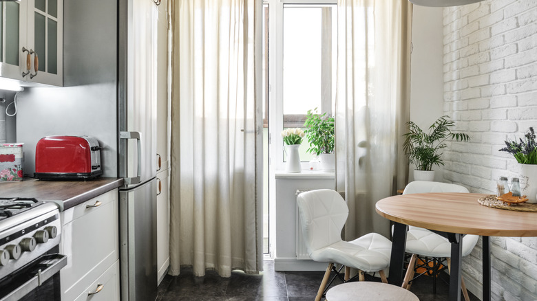Small kitchen with cabinets and a range and a small dining set