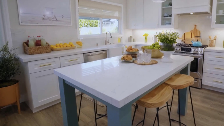 A kitchen with a table in the middle and stools
