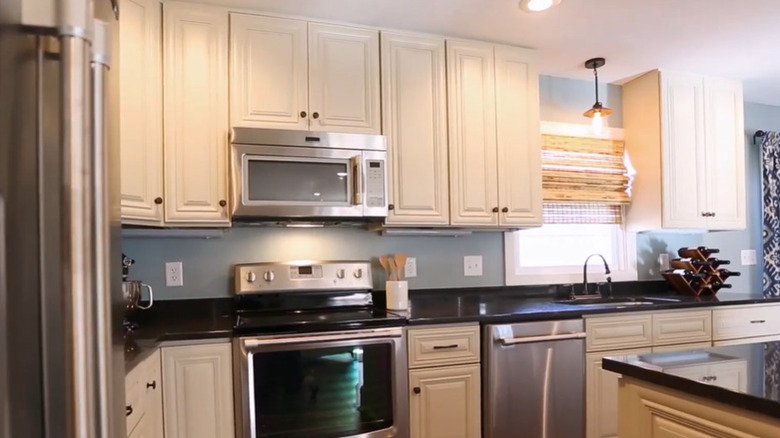A kitchen with light-colored cabinets that extend to the ceiling