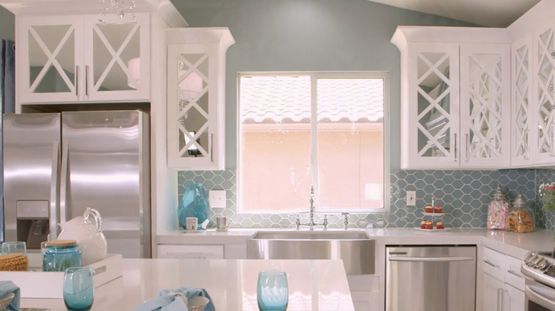 A kitchen with mirrored white kitchen cabinets