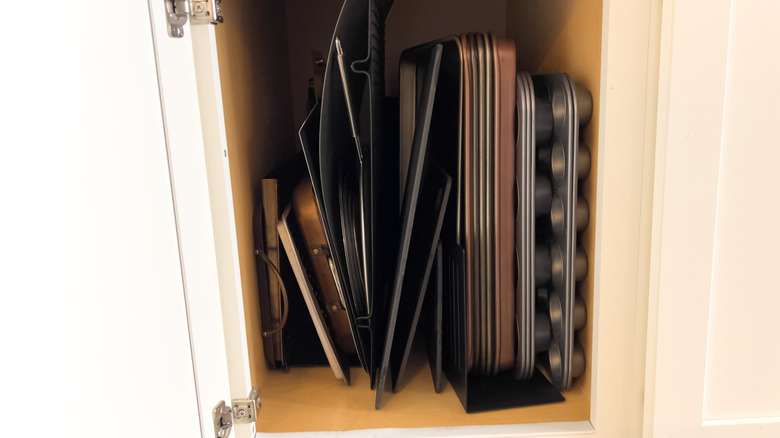 Messy cabinet area with multiple baking sheets taking up space