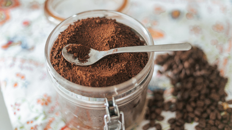 Dry coffee grounds in open glass jar with spoon