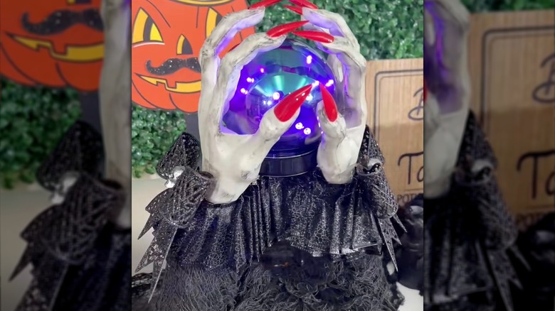 A DIY fortune teller project featuring two hands with red nails holding a glowing orb