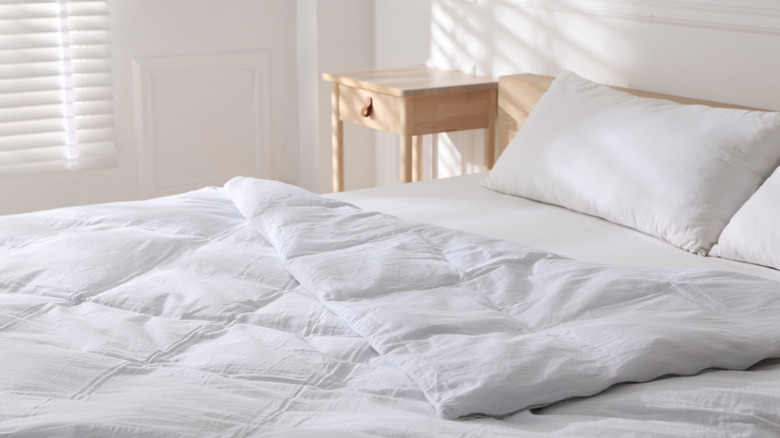 A white duvet on a bed in an all-white bedroom.