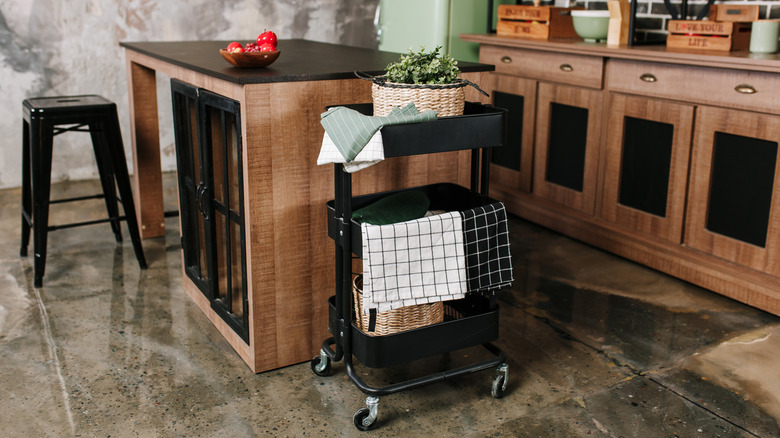 A kitchen with a rolling bar cart for extra storage.