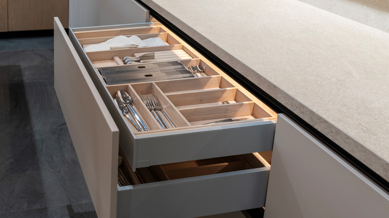 An open kitchen drawer with tiered cutlery dividers.