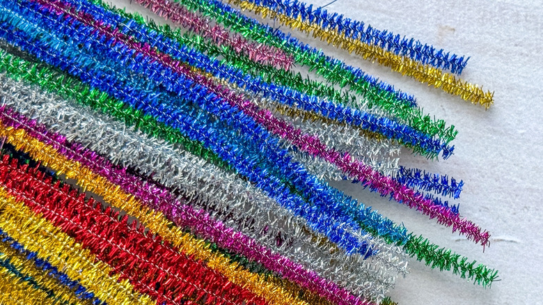 Multicolored metallic pipe cleaners sit on a table ready for crafting.