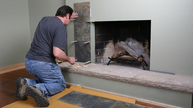man tiling his fireplace surround
