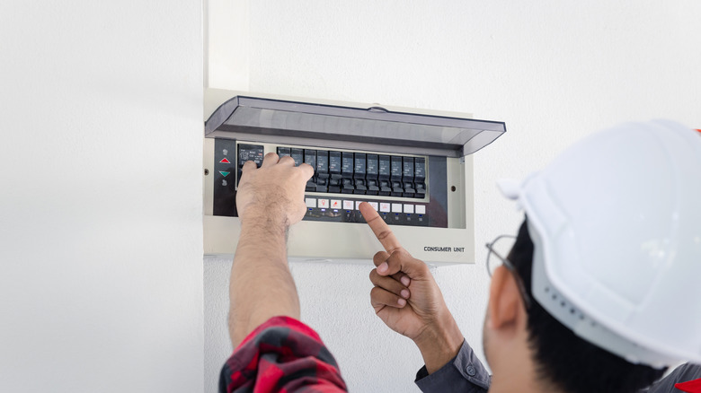 Two electricians turn off the power at a residential breaker box