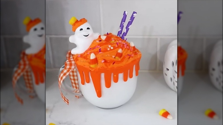 A painted Dollar Tree mug holds a faux Halloween drink decorated with a plastic ghost.