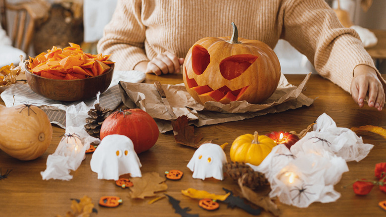 A person making a range of Halloween decorations including a carved pumpkin and mini ghosts