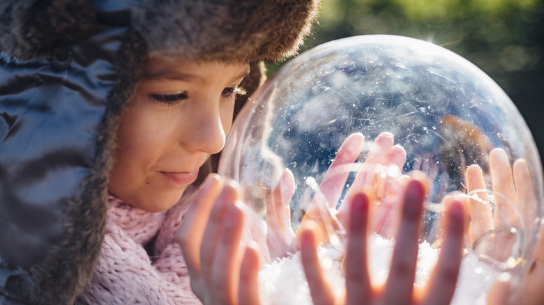 A child looking inside a large snow globe