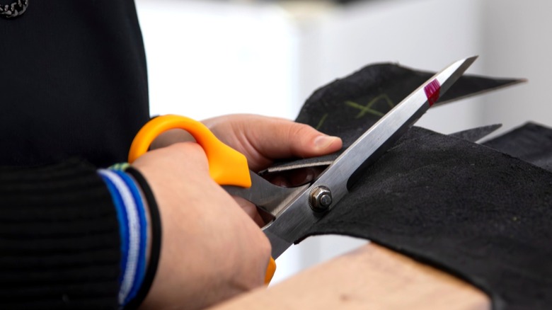 Person cutting out black eyes for ghost decor from black felt