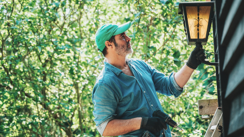 Person installing exterior light on home
