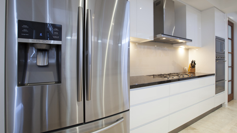 A shiny stainless steel fridge in a crisp white kitchen
