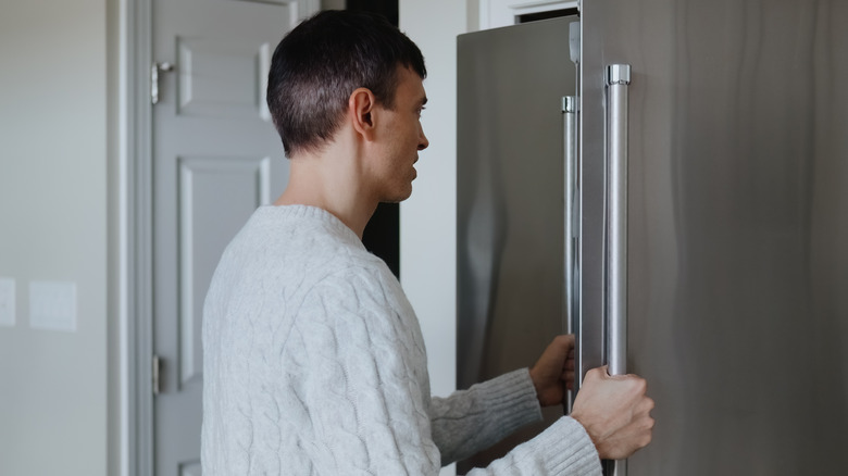 A person opening up a stainless steel fridge