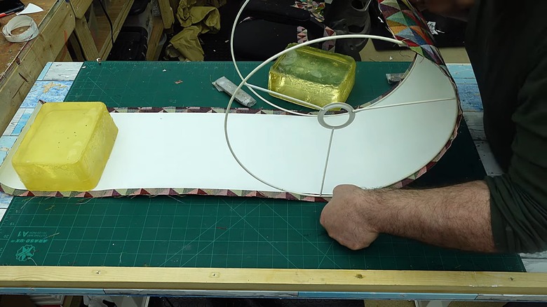 Person making lampshade with interior liner on fabric.