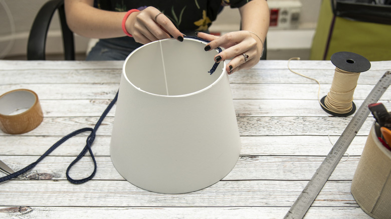 Woman's hands work on making a white lampshade.