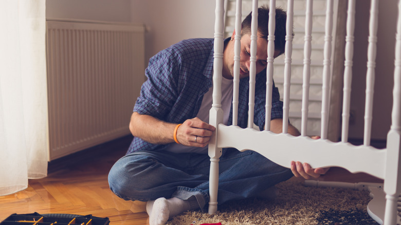 A man with a partially assembled baby crib